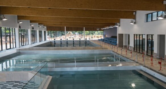 Centre aqualudique moderne avec bassins intérieurs et extérieurs, espaces de jeux d’eau et zones de détente accueillant le public.
